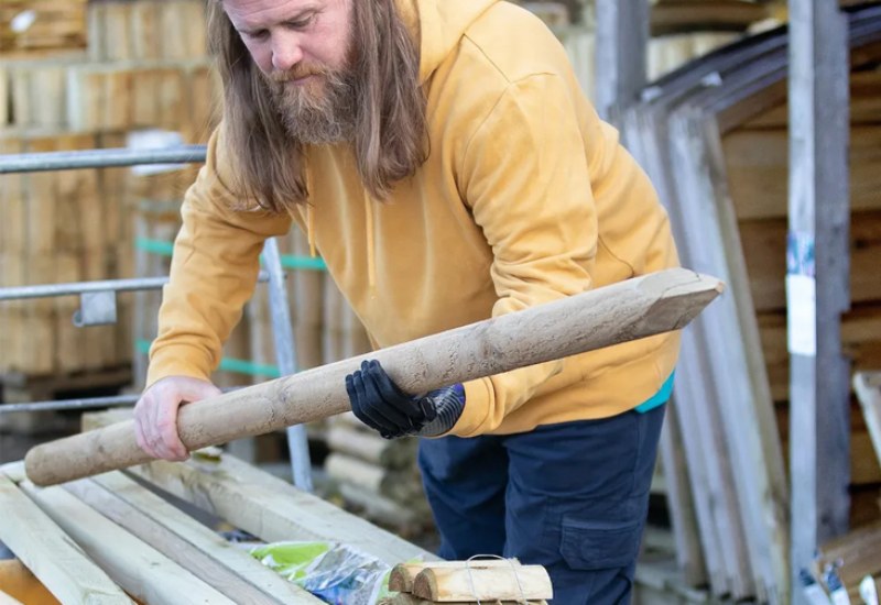 A man with a prosthetic arm is holding a wooden plank in New York, New Jersey, & Connecticut