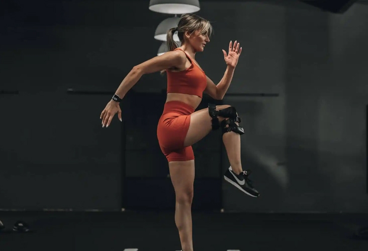A woman in a red cloth performs a squat in New York, showcasing her leg strengthening braces